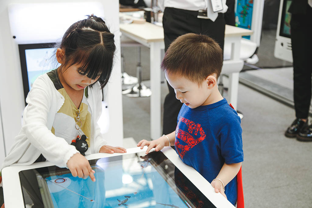 twee kinderen druk aan het spelen met de interactieve spelsystemen van IKC